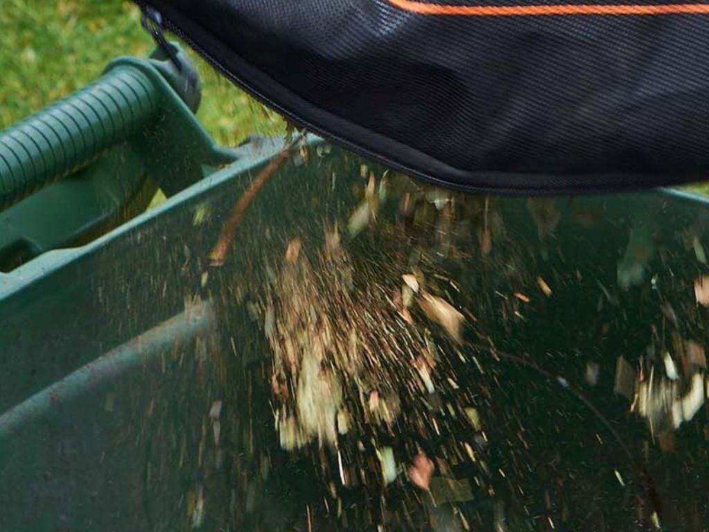 vidage du sac d'un soufleur-aspirateur de jardin dans une poubelle